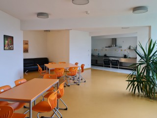 Foto: Internat Reichenbach, 1. Etage, Aufenthaltsraum mit orangen Sitzgruppen und Blick in die Küche