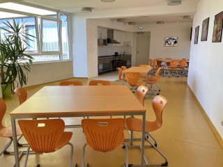 Foto: Internat Reichenbach, 1. Etage, Aufenthaltsraum mit drei orangen Sitzgruppen und Blick in die Küche